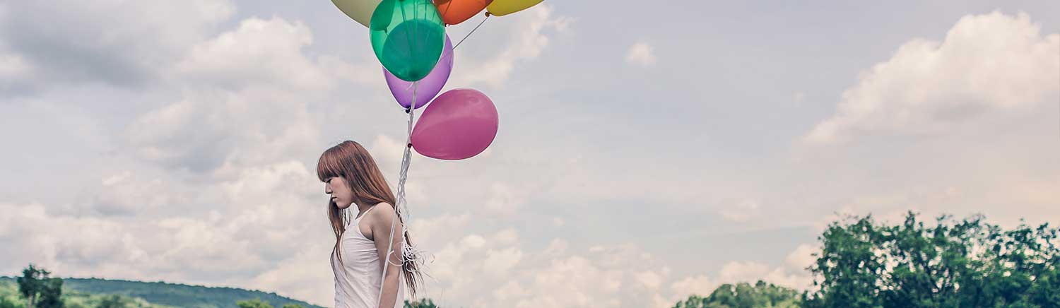 Een meisje dat een bos ballonnen in de lucht houdt.